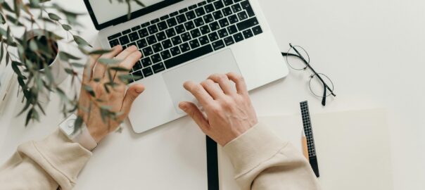 Free An overhead view of a person working on a laptop in a minimalist home office setting. Stock Photo